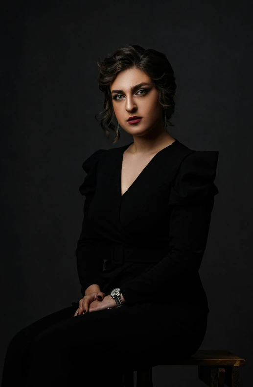 a woman in a black dress sitting on a chair, inspired by Yousuf Karsh, pexels, young middle eastern woman, portrait n - 9, concert, cinematic outfit photo