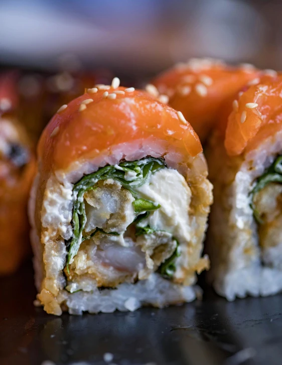 three sushi rolls on a counter with a green topping