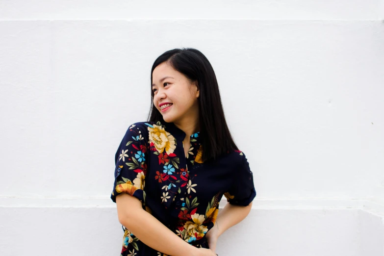 a woman standing in front of a white wall, inspired by Ruth Jên, pexels contest winner, smiling for the camera, avatar image, navy, floral