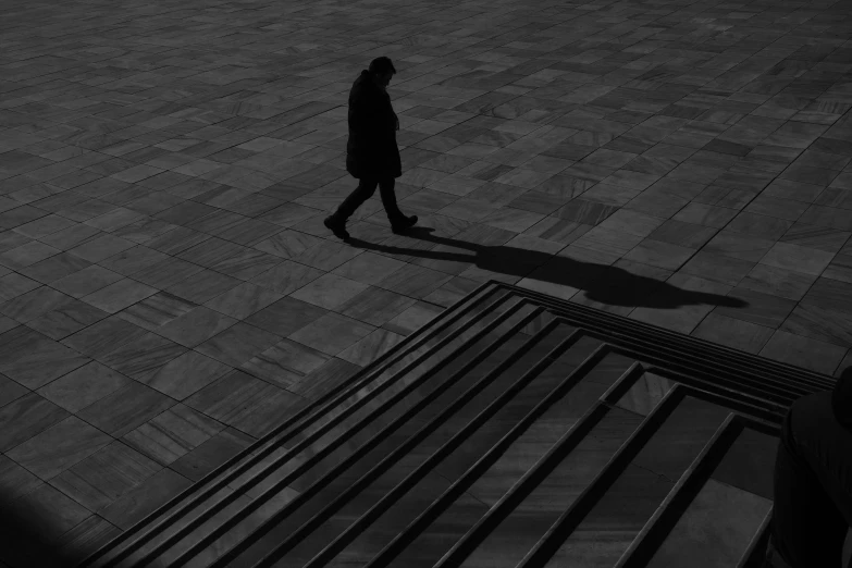 a black and white photo of a person walking, a black and white photo, by Constantine Andreou, pexels contest winner, minimalism, deep shadows and colors, steps, alexey gurylev, people on the ground