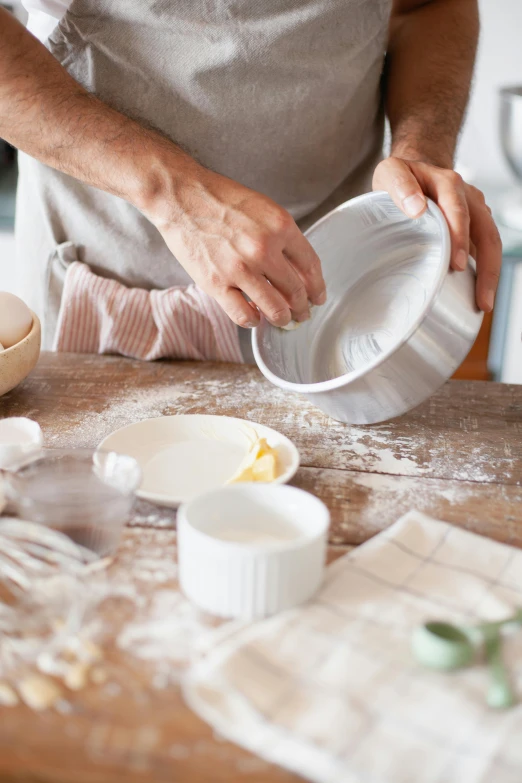 a person in a kitchen preparing food on a table, a still life, trending on pexels, covered in white flour, bowl, white ceramic shapes, banner