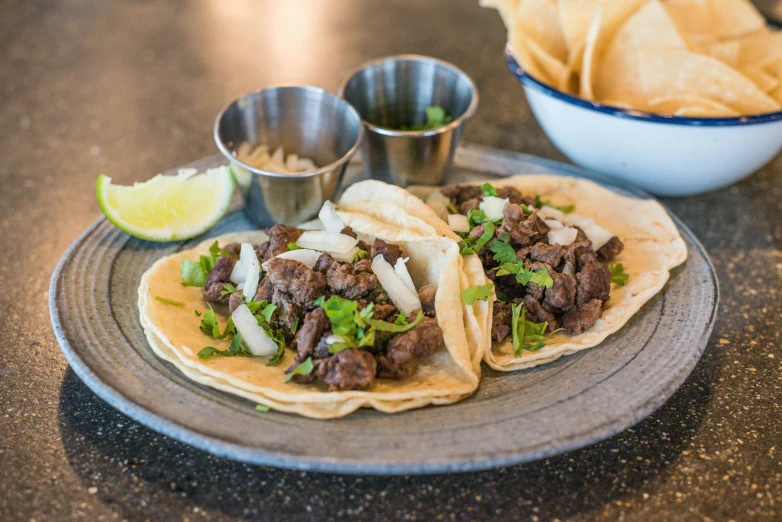 a plate topped with two tacos next to a bowl of chips, pexels contest winner, dau-al-set, donkey ears, thumbnail, exterior shot, westside