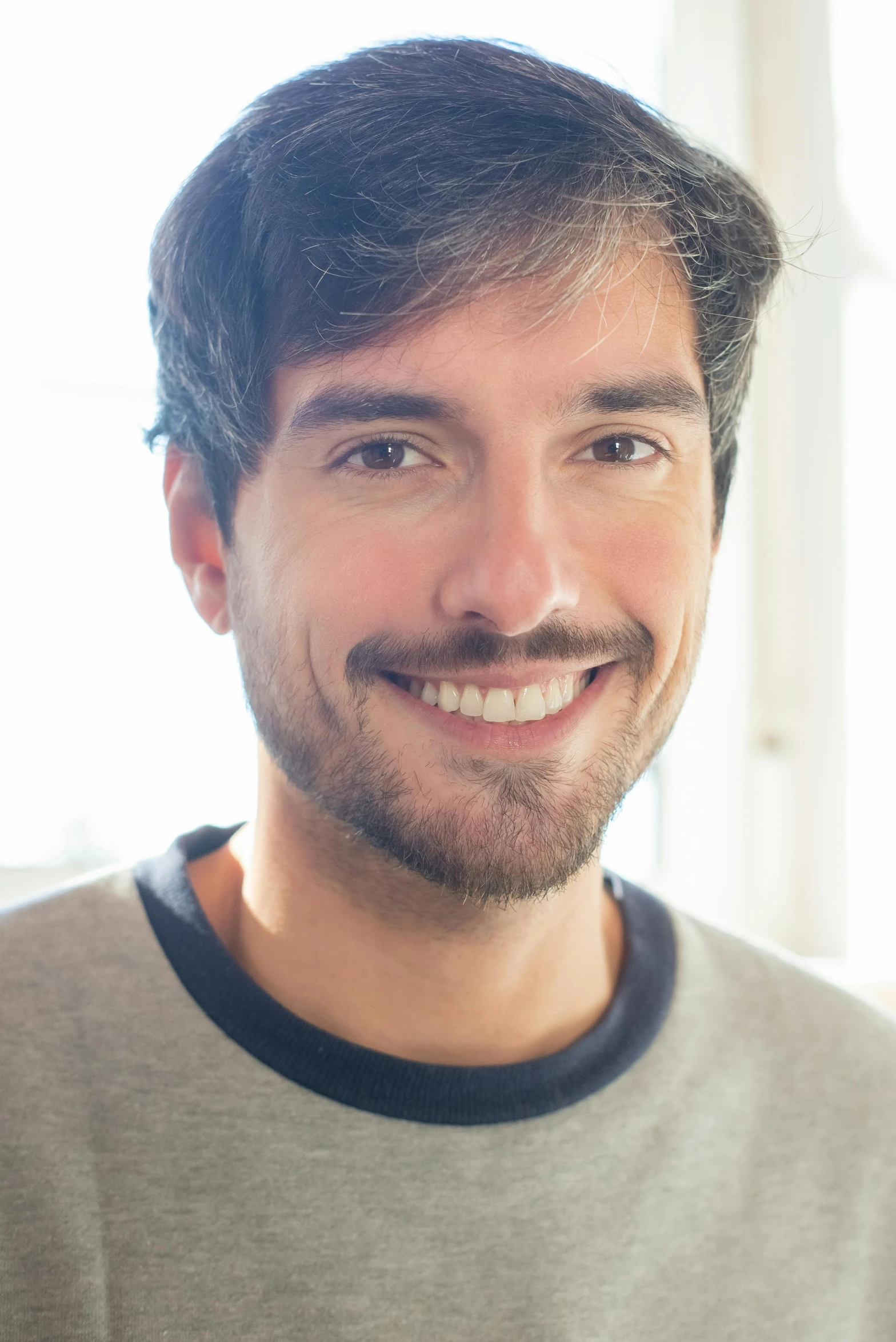 a smiling man standing in front of a window, inspired by Germán Londoño, happening, light stubble beard, nathan fielder, close up portrait photo, young spanish man