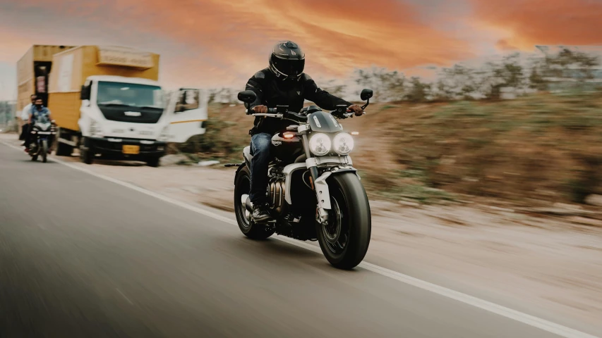 a man riding on the back of a motorcycle down a road, triumph, avatar image