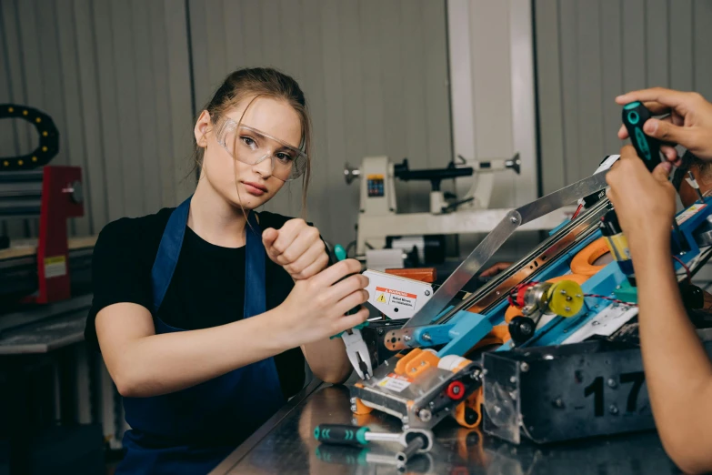 a couple of women standing next to each other, pexels contest winner, arbeitsrat für kunst, scrap metal on workbenches, girl wearing round glasses, teenage engineering moad, 15081959 21121991 01012000 4k