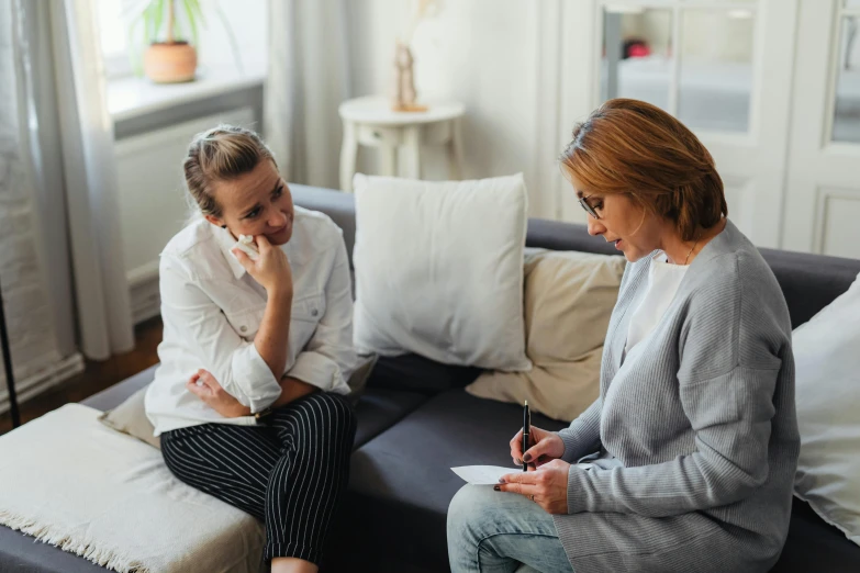 two women sitting on a couch talking to each other, health supporter, amanda lilleston, stressing out, on a white table