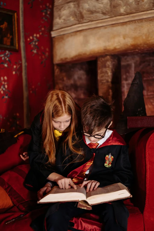 a couple of kids sitting on top of a red couch, marauders map, wearing a luxurious velvet robe, a brightly coloured, magic school uniform