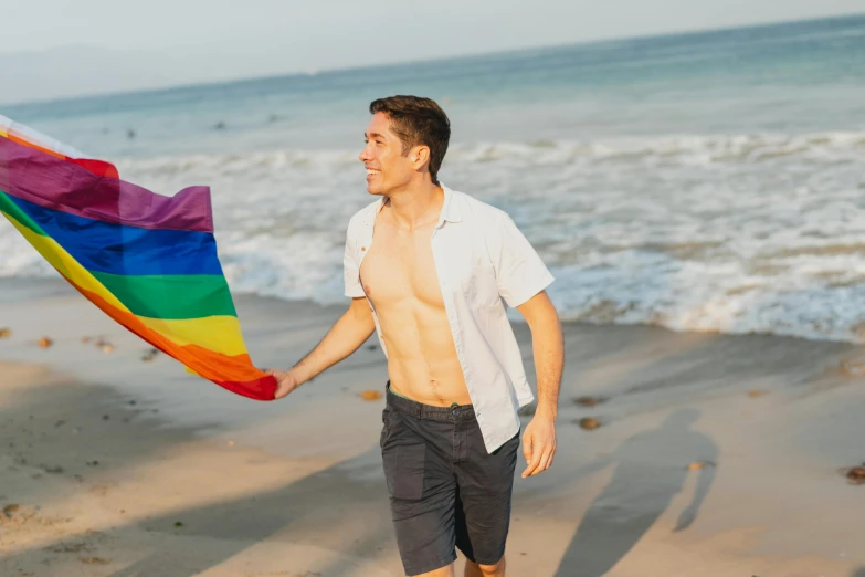 a man walking on a beach holding a rainbow flag, a photo, lean man with light tan skin, lance, white male, profile image