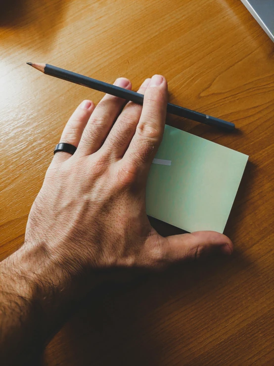 a person writing on a piece of paper with a pencil, by Sven Erixson, pexels contest winner, ink on post it note, green and black, hand model, lgbtq