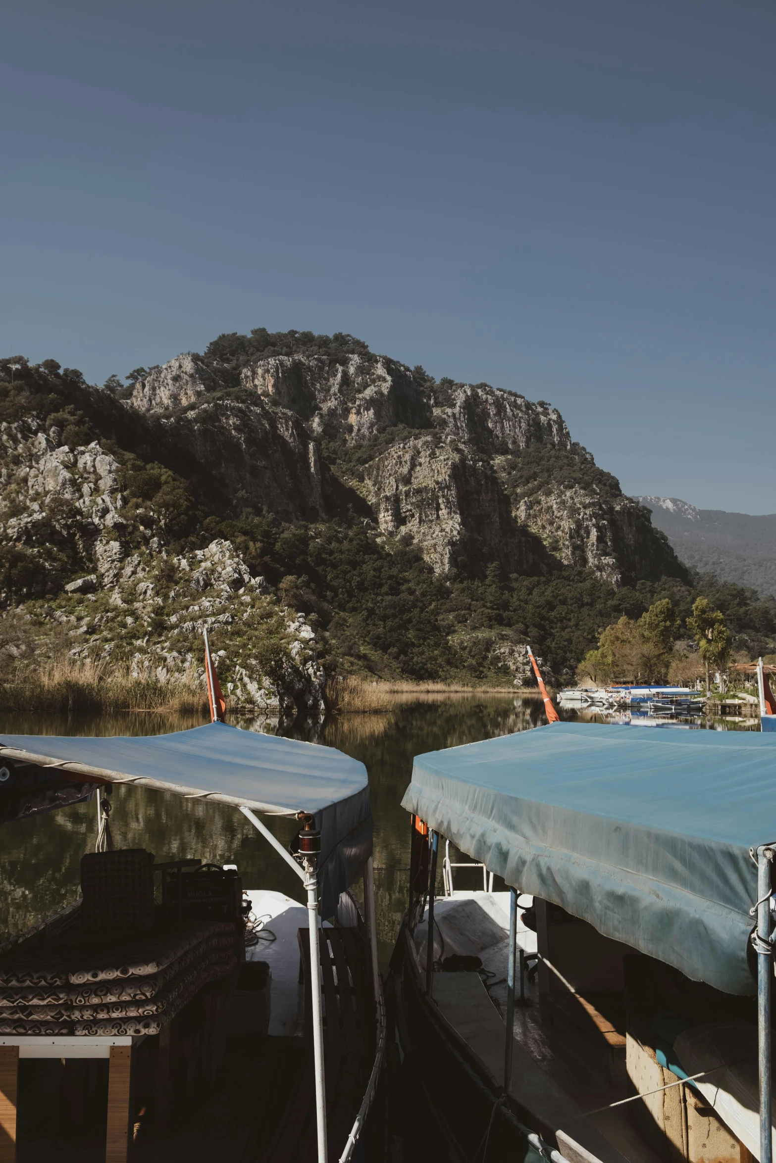 a couple of boats sitting on top of a lake, les nabis, mountains surrounding, symmetrical face orelsan, floating cars, trees and cliffs