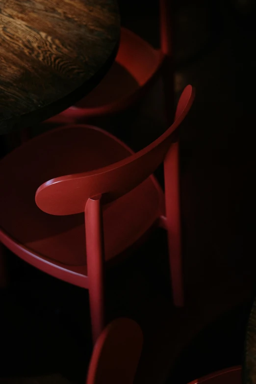 a red chair sitting next to a wooden table, by Doug Ohlson, night color, cafe lighting, hiding, lacquered