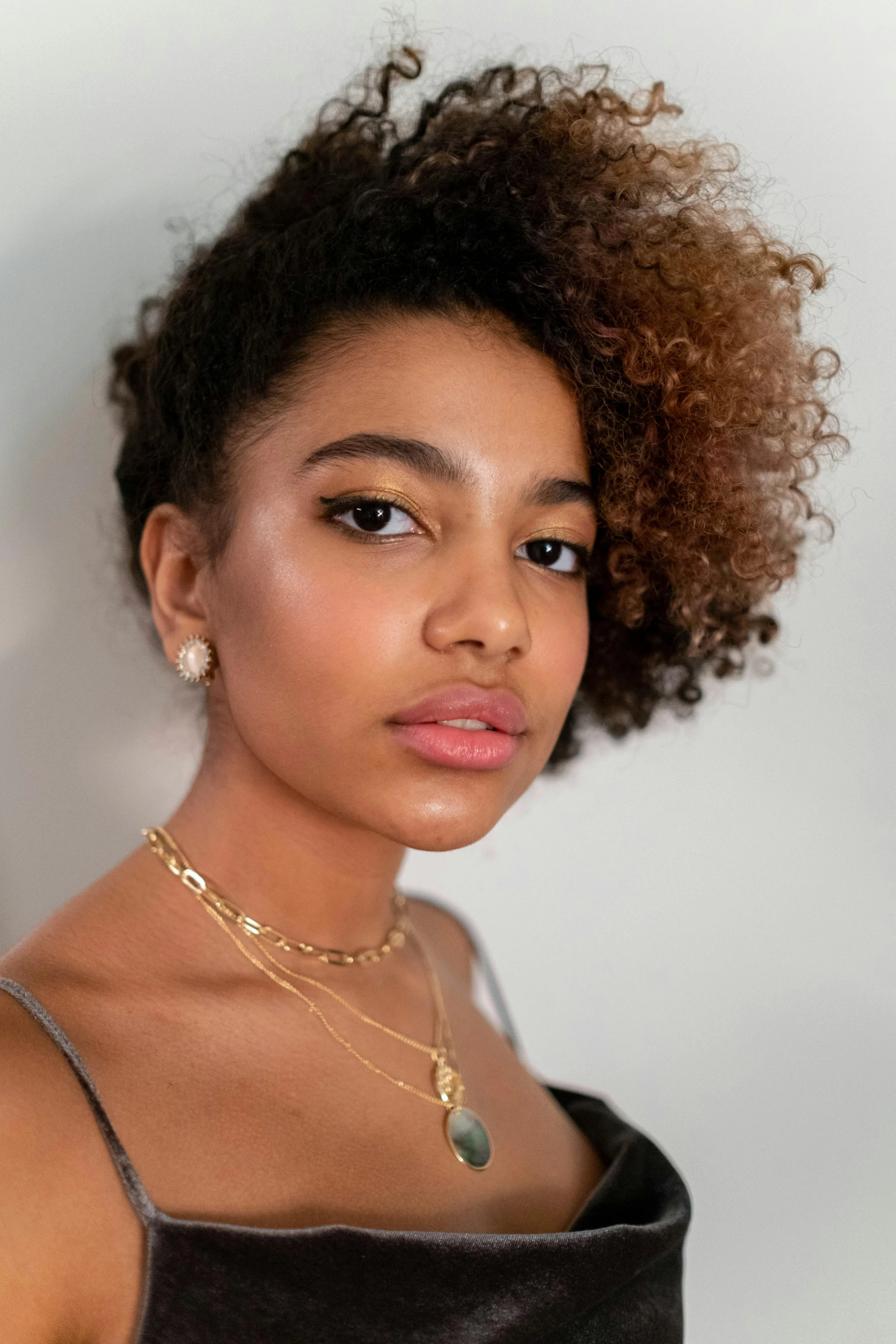 a woman in a black dress posing for a picture, light-brown skin, wearing gold detailed choker, frizzy hair, aida muluneh