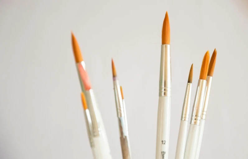 a number of different paint brushes in a cup