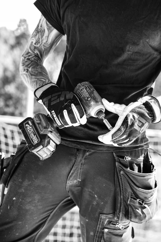 a black and white photo of a man on a skateboard, a black and white photo, pexels, photorealism, tool belt, chainsaw attached to hand, holding arms on holsters, worksafe. instagram photo