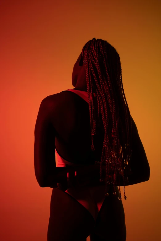 a woman with dreadlocks standing in front of a red and yellow background, trending on pexels, afrofuturism, back light contrast, shapely derriere, braided hair. nightime, sza