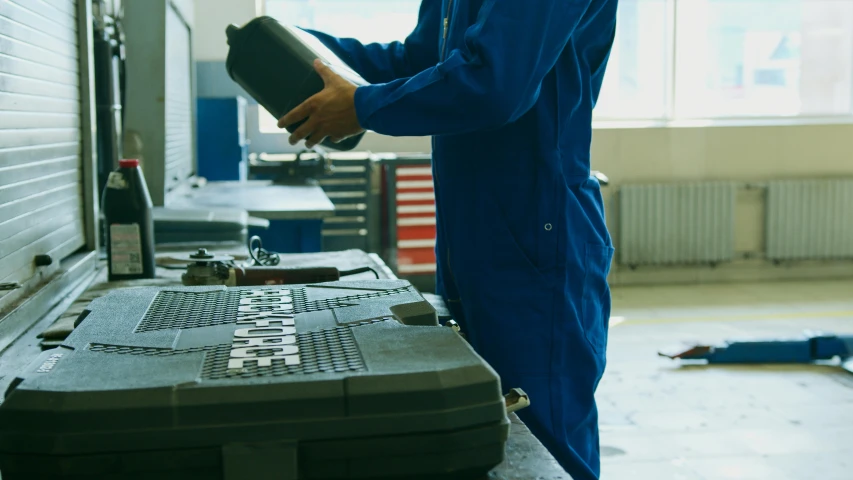 a man working on a machine in a factory, an album cover, pexels contest winner, renaissance, add text: auto repair, holding a battery, blue, formula 1 garage