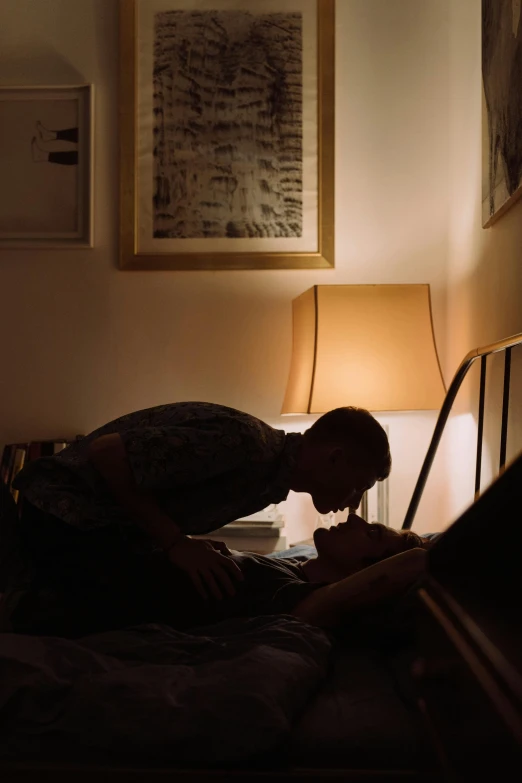 a man laying on a bed in a dark room, inspired by Nan Goldin, unsplash, romanticism, kissing together, ignant, emerging from her lamp, evening sunlight