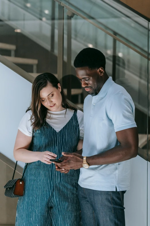 a man and a woman standing next to each other, happening, pregnant, looking at his phone, black man, charli bowater and artgeem