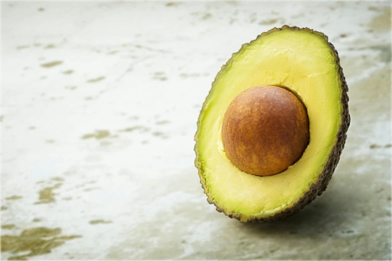 an avocado cut in half on a table, trending on pexels, gold, fan favorite, olive thigh skin, historical image