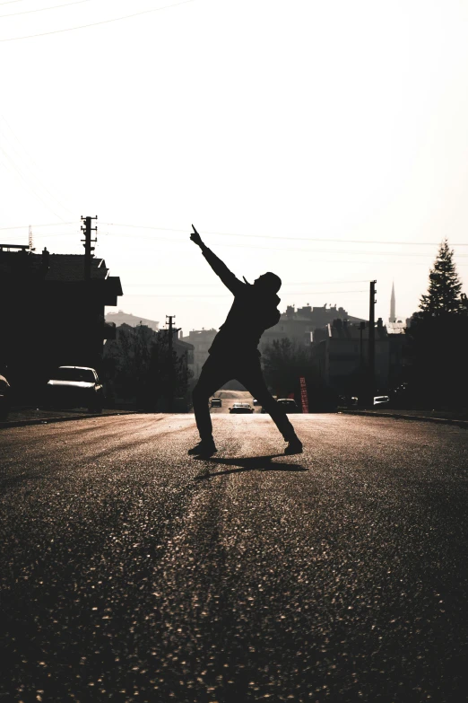 a man riding a skateboard down the middle of a street, an album cover, pexels contest winner, silhouette :7, pose(arms up + happy), standing on rocky ground, 2019 trending photo