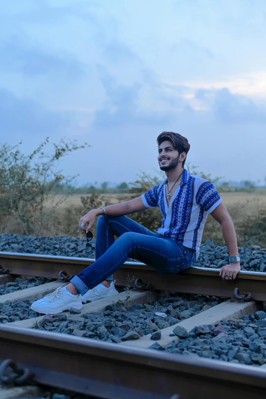 a man sitting on top of a train track, inspired by Saurabh Jethani, pexels contest winner, samikshavad, portrait full body, profile image, lgbtq, wearing a shirt and a jean