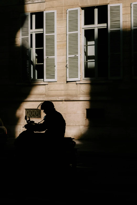 a person sitting on a motorcycle in front of a building, pexels contest winner, paris school, back lit, writing a letter, sittin, eerie person silhouette