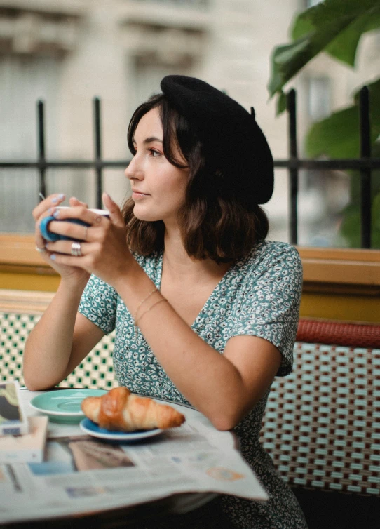 a woman sitting at a table with a cup of coffee, a portrait, by Julia Pishtar, trending on unsplash, wearing a french beret, avatar image, square, gal gadot china plate