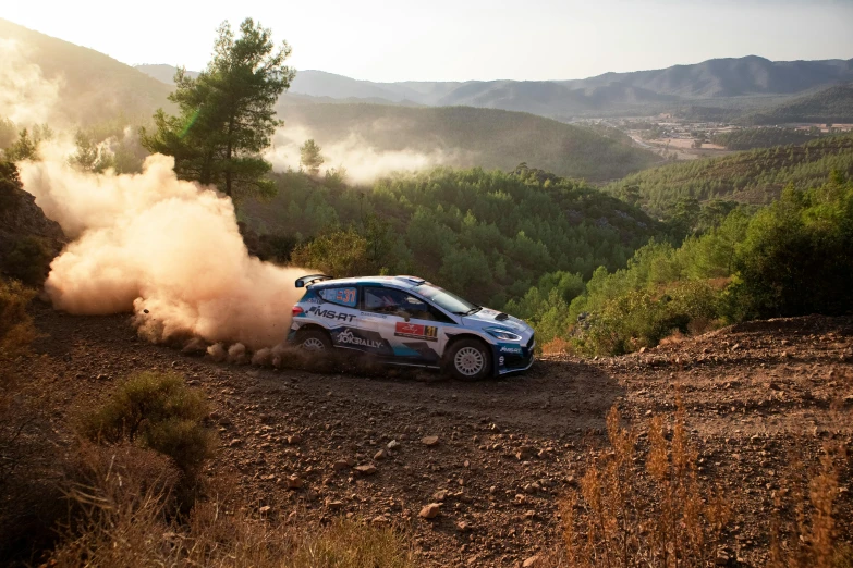 a subaru driving around a hill on the dirt road