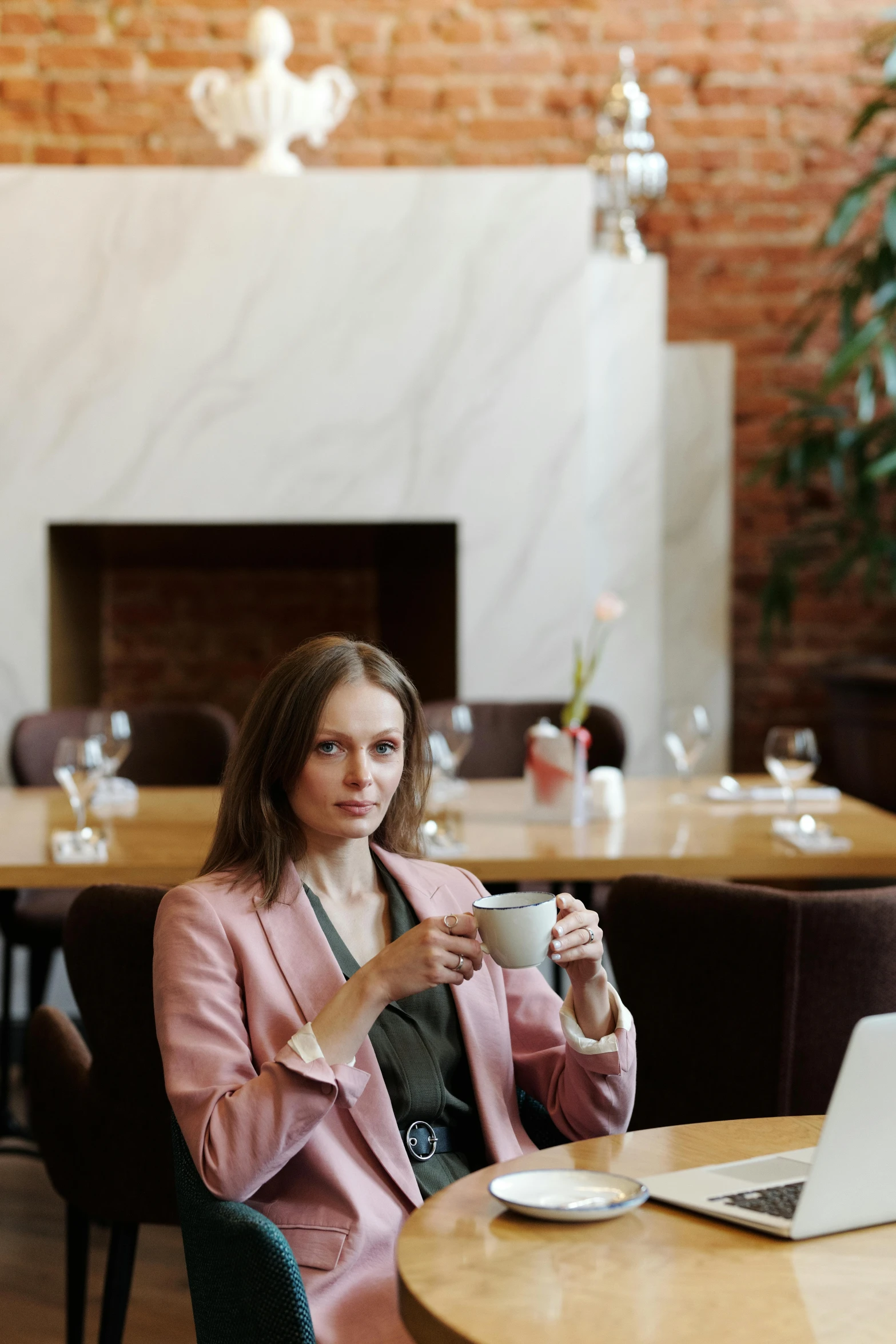 a woman sitting at a table with a cup of coffee, neo kyiv, wearing business casual dress, wearing a light - pink suit, profile image