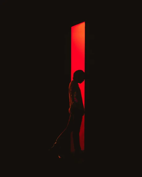 a person standing in front of a red door, an album cover, inspired by Elsa Bleda, pexels contest winner, black silhouette, bisexual lighting, about to step on you, light show
