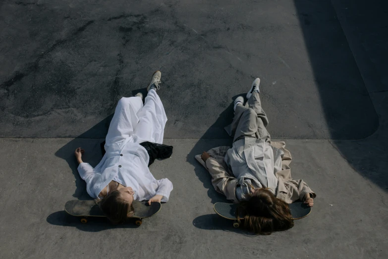 a couple of people laying on top of a skateboard, pexels contest winner, realism, dressed in white robes, 2 techwear women, alessio albi and shin jeongho, wearing a suits