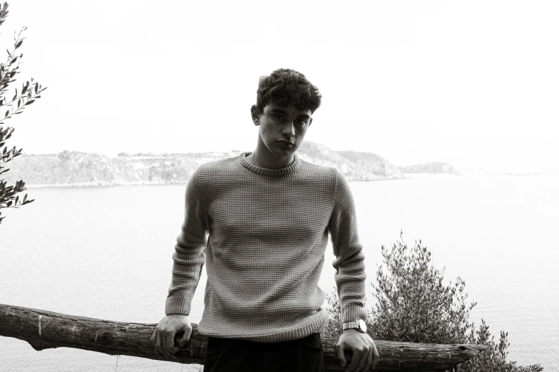 a black and white photo of a man holding a log, inspired by Luca Zontini, wearing casual sweater, seaview, riccardo scamarcio, portrait”
