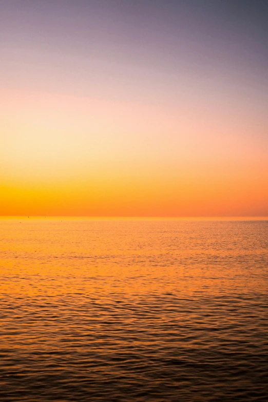 a large body of water with a sunset in the background, a picture, yellow and orange color scheme, marbella, ((sunset)), fading off to the horizon