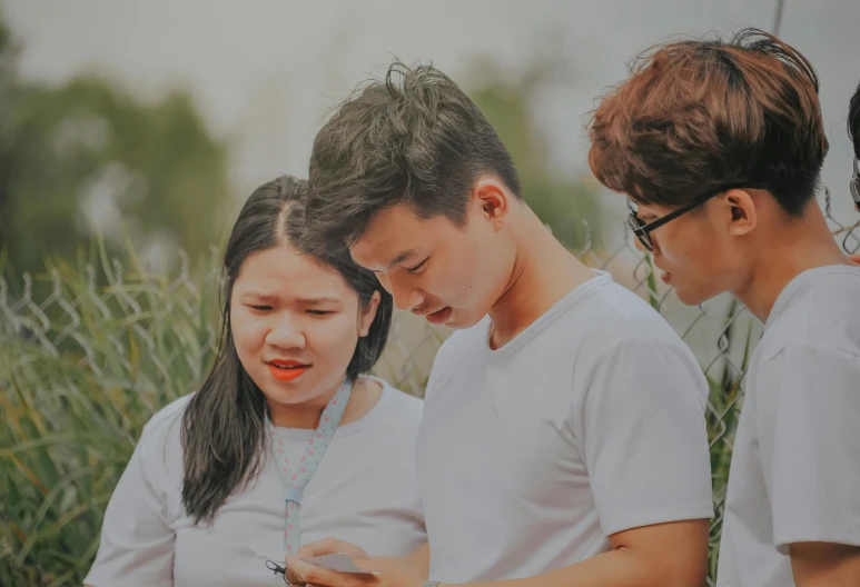 a group of people looking at a cell phone, trending on pexels, south east asian with round face, contemplating, square, high resolution image