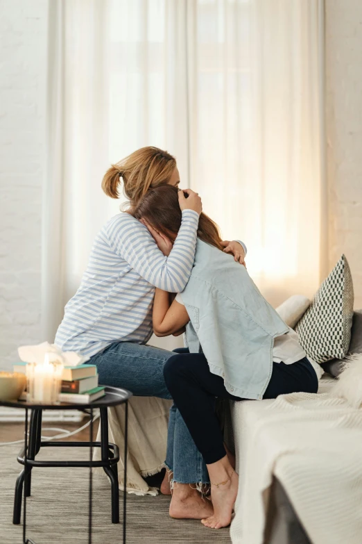 a couple of people that are sitting on a couch, pexels contest winner, romanticism, hugging each other, woman crying, motherly, back facing