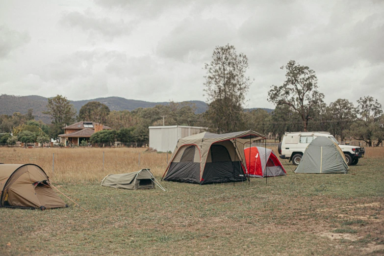 a group of tents sitting on top of a grass covered field, a portrait, australian bush, at home, an open field, lachlan bailey