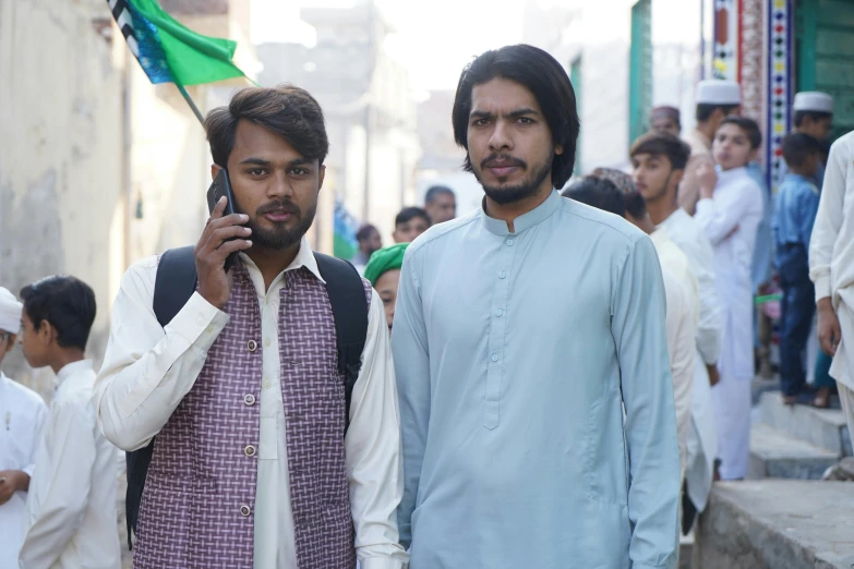 two young men pose for the camera, in front of a crowd