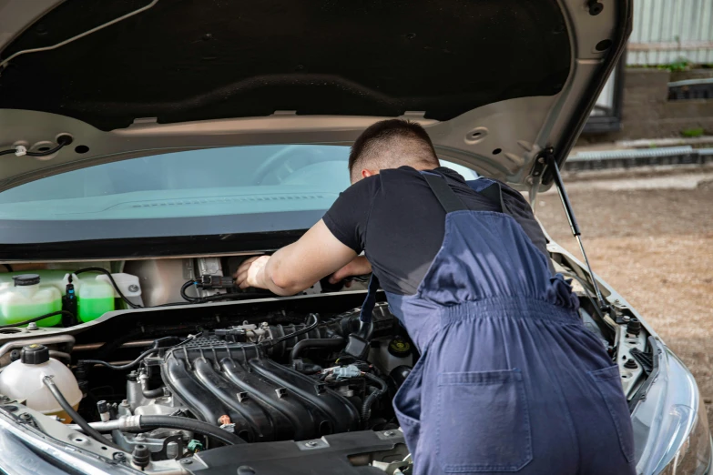 a man in overalls looking under the hood of a car, a picture, shutterstock, lachlan bailey, 15081959 21121991 01012000 4k, profile image, pistons and bolts