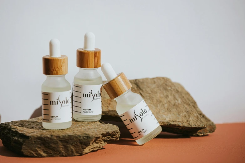 a couple of bottles sitting on top of a rock, an album cover, by Micha Klein, trending on pexels, photorealism, photoshoot for skincare brand, made of bamboo, mihoyo, in a row