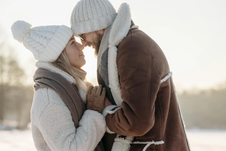 a man and woman standing next to each other in the snow, pexels contest winner, romanticism, wearing wool hat, profile image, cuddling, promotional image