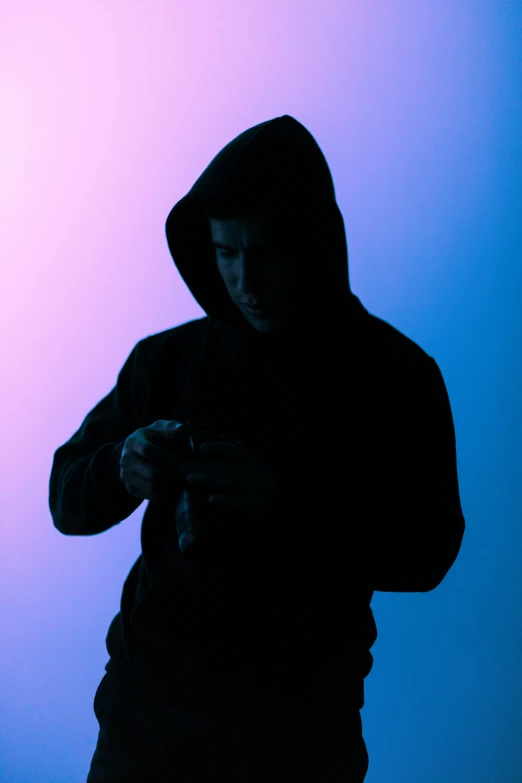 a man in a hoodie looking at his cell phone, pexels, digital art, strong silhouette, looking to camera, like a catalog photograph, holding handgun