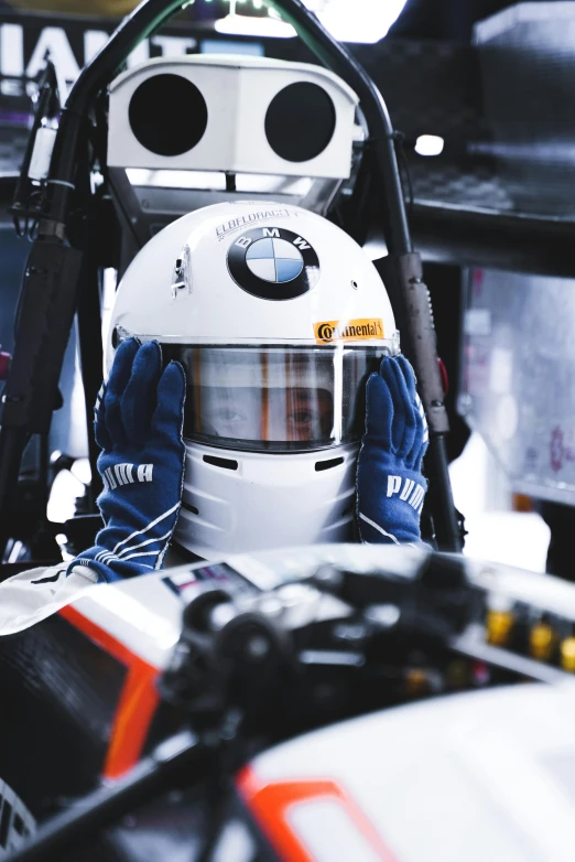 a man sitting in the cockpit of a race car, bmw, white helmet, liam brazier, armor focus on face