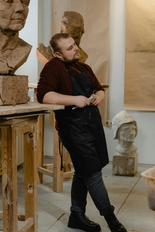 a man standing next to a bust of a man, a marble sculpture, inspired by Károly Markó the Elder, pexels contest winner, arbeitsrat für kunst, in a workshop, profile image, made of clay, wide full body