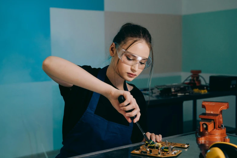 a woman sitting at a table in front of a plate of food, red hot soldering iron, wearing goggles, school class, pictured from the shoulders up