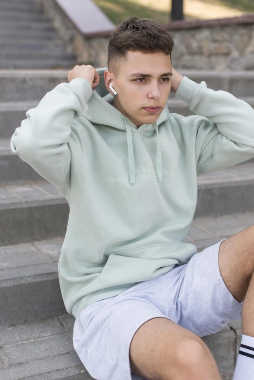 a young man sitting on a set of stairs, trending on pexels, renaissance, pastel green, hoody, ice blue, plain