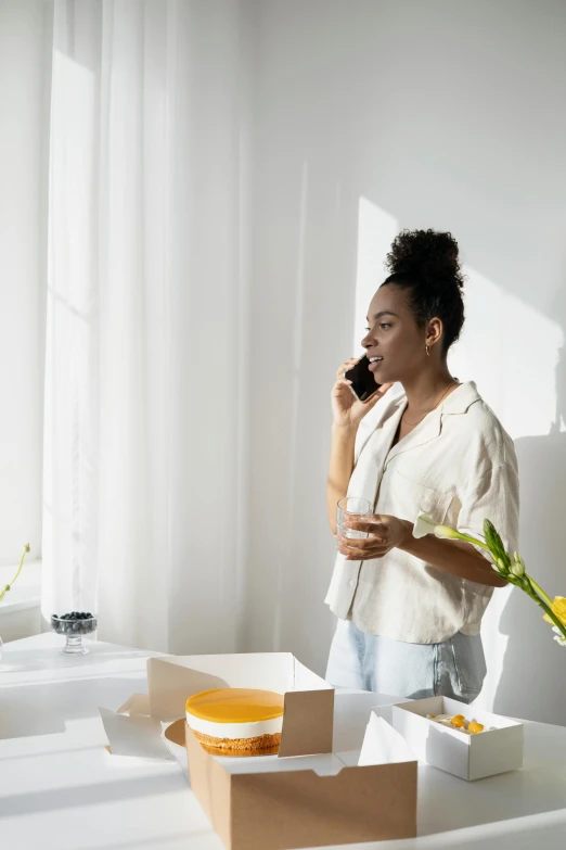 a woman standing in a room talking on a cell phone, coffee smell, filled with natural light, on a white table, dark-skinned