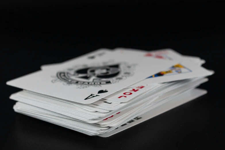 a stack of playing cards sitting on top of a table, a screenshot, by Adam Marczyński, pexels contest winner, white moon and black background, plain background, 3/4 view from below, online casino logo