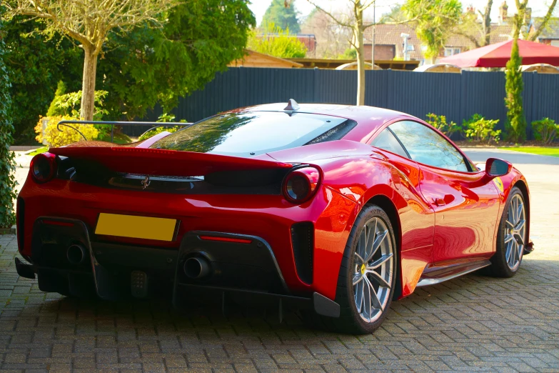 the red sports car is parked in front of some bushes