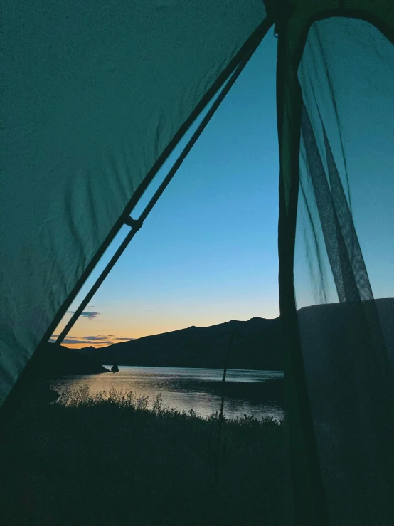 a view of a body of water from inside a tent, by Jessie Algie, unsplash contest winner, filtered evening light, lake blue, campy, low quality photo