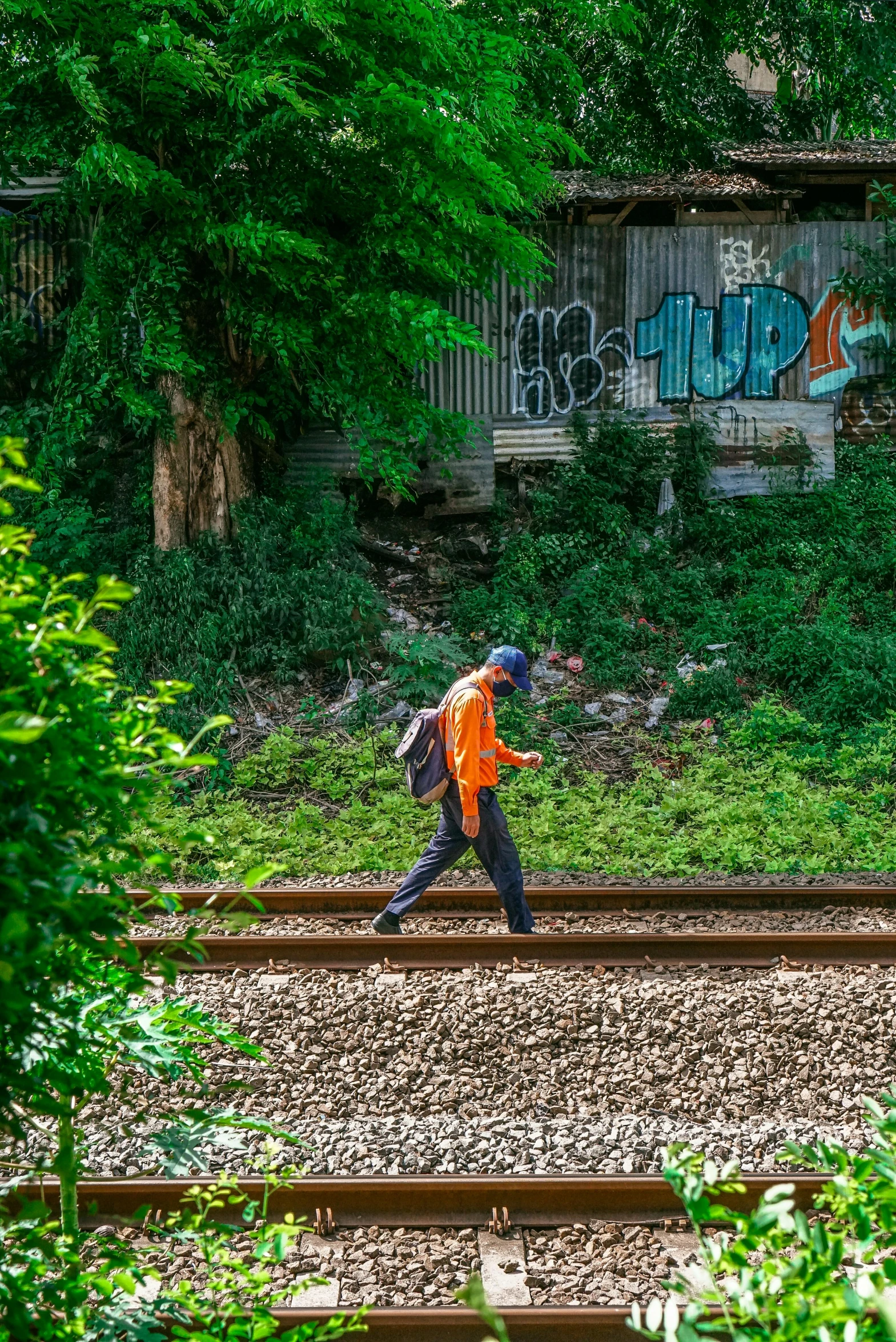 there is a man walking along the train tracks